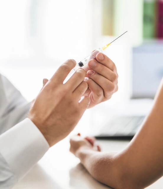Lekarz szykuje się do podania pacjentce szczepionki przeciw HPV, zbliżenie na dłonie, strzykawkę i ramię