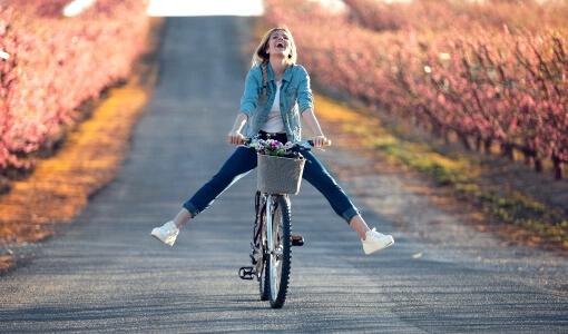 Młoda kobieta jedzie na rowerze polną drogą
