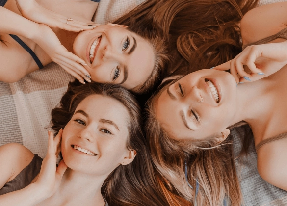 Trzy uśmiechnięte dziewczyny leżą na kocu